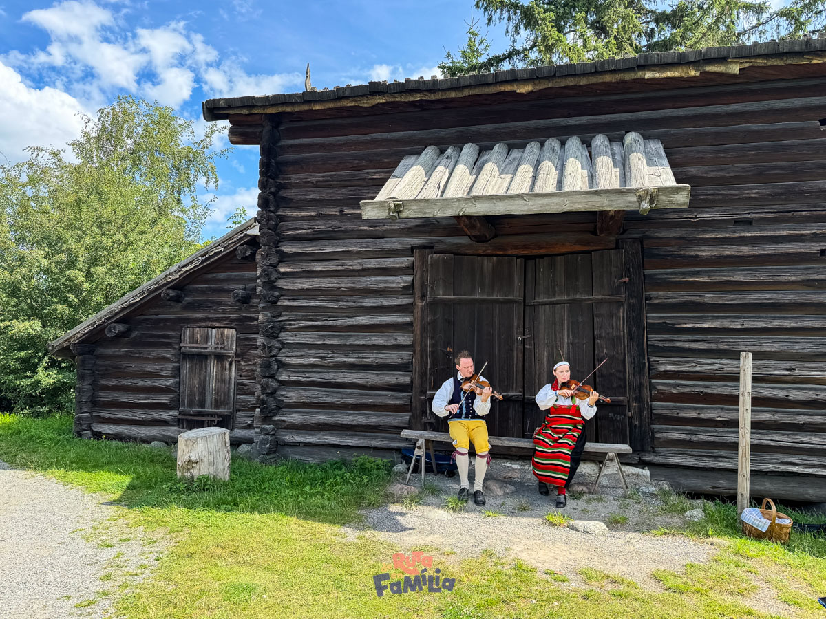 musicos_tradicionales_skansen_derutaenfamilia Músicos con trajes tradicionales tocando frente a una construcción de madera en Skansen